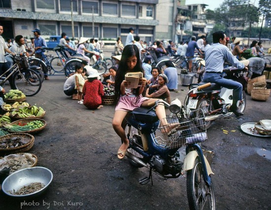 Bé gái đọc sách trong lúc chờ mẹ mua hàng ở chợ, 1990.