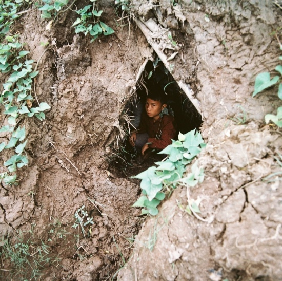 Em bé ngồi trong hầm tránh bom.